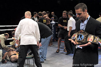 The aftermath.  Lutter attended to by doctor, Rivera in his corner in the middle, and promoter Tom Hafers holding the belt on the right.  UFC Pez Dana White is bending down with the black shirt and jeans in the middle of the ring talking to Lutter but his face is obscured by someone else.